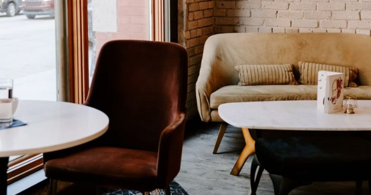 Velvet armchair, round tables and a sofa beside a brick wall