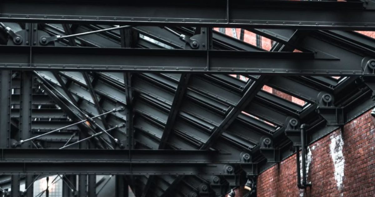 Black steel roof beams against a brick wall in an industrial interior