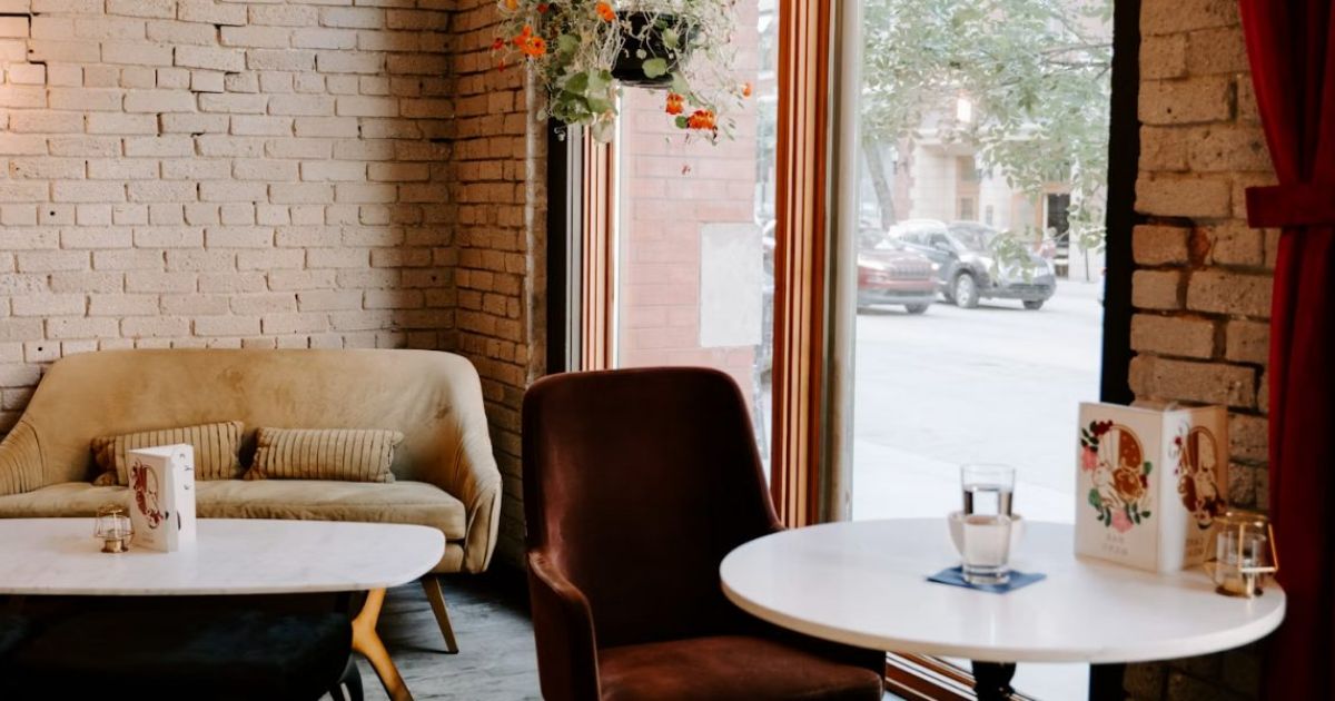 Armchair, sofa and round tables beside a brick wall and a large window